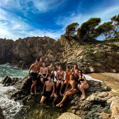 a group of people on a rock next to a body of water