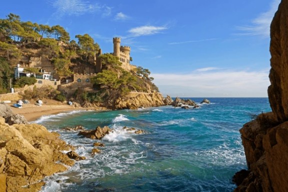 a rocky island in the middle of a body of water with McWay Falls in the background